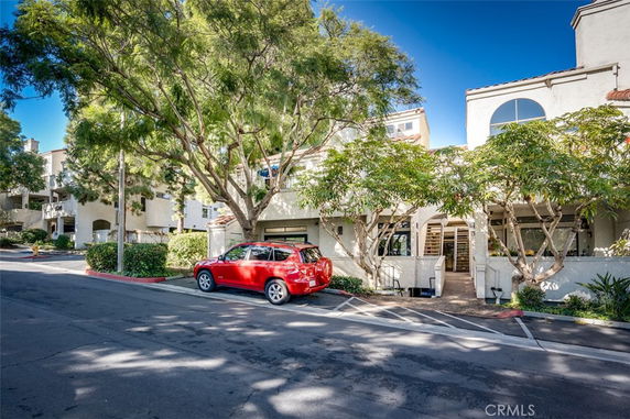 Front view of a multi-story building with trees and a red car parked in front.