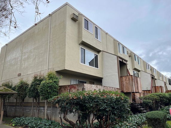 Front view of a multi-story building with beige exterior and large windows.