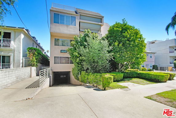 Front view of a multi-story residential building with a driveway leading to underground parking.