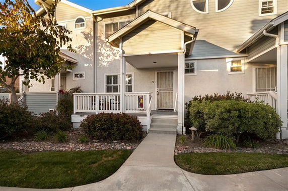 Front view of a two-story townhouse with a small porch and white railing.