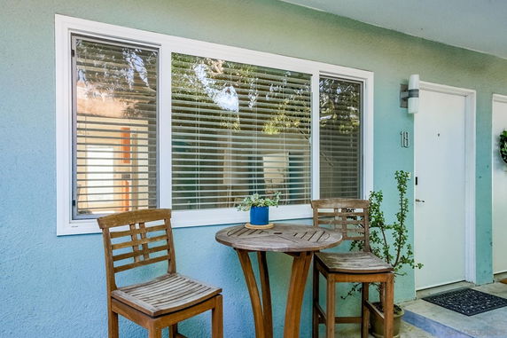 Front view of a residential building entrance with a small patio table and chairs.