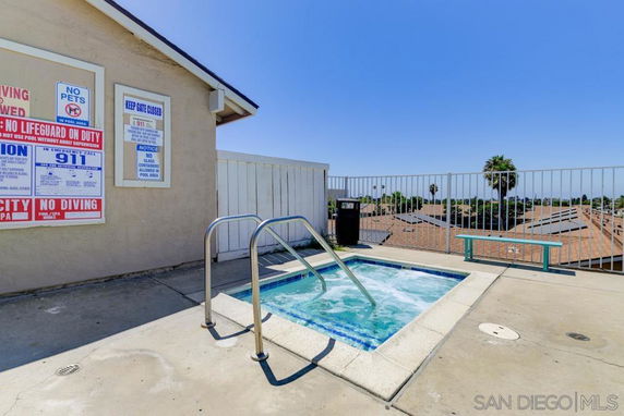 A rooftop area with a small jacuzzi and surrounding railings.
