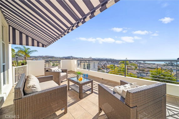 Panoramic view from a balcony with patio furniture and an awning.