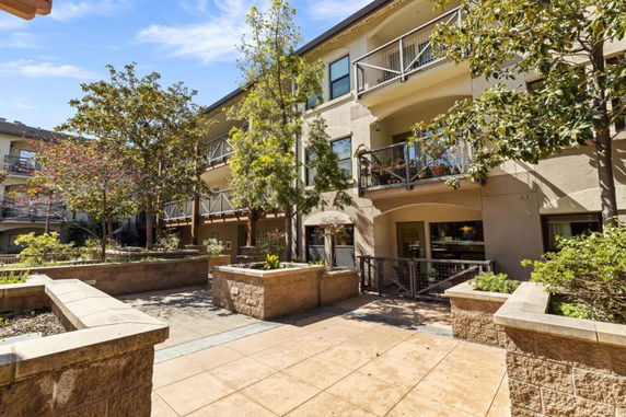 Front view of a multi-story building with balconies and landscaped surroundings.