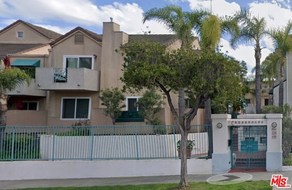 Front view of a multi-story residential building with balconies and a gated entrance.