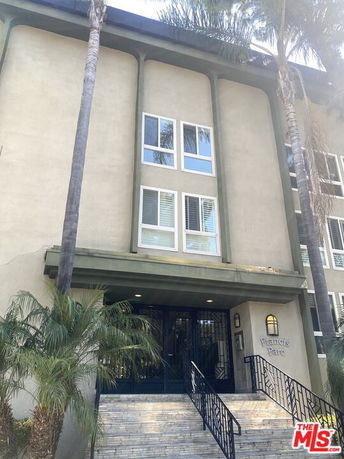 Front view of a multi-story building with large windows and an entrance stairway.