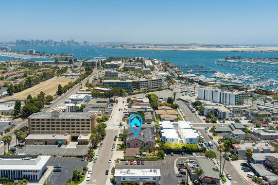 Panoramic view of a coastal city with buildings, roads, and marina, overlooking a bay.