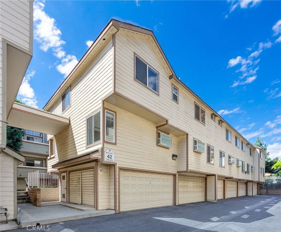 Front view of a multi-story residential building with garages on the ground level.