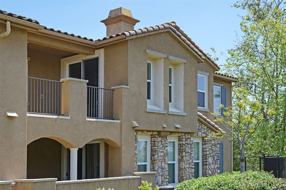 Front view of a two-story house with a balcony and stone accents.