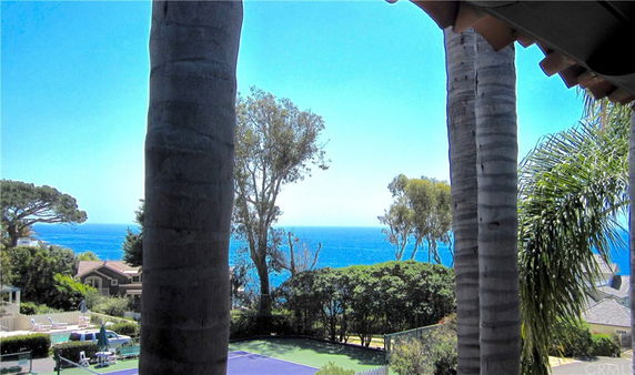 Panoramic view of an ocean with trees and buildings along the coastline.