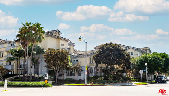 Front view of a multi-story building with balconies and a tiled roof.