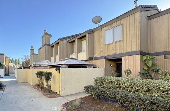 Front view of a two-story townhouse with a fenced patio area.