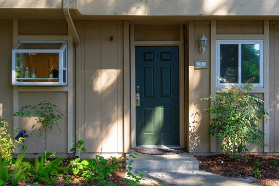 Front view of a house with a dark green door and two windows.