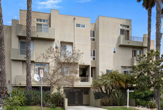Front view of a modern multi-story building with balconies and a gated entrance.