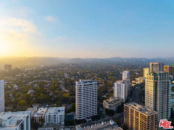 Wide-angle view of a cityscape with tall buildings and a distant hilly horizon.
