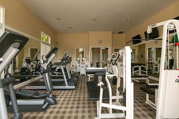 Indoor gym area with exercise equipment including treadmills and weight machines.