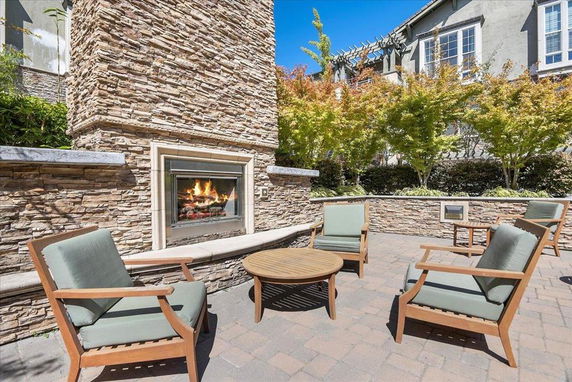 Outdoor seating area with armchairs around a stone fireplace.