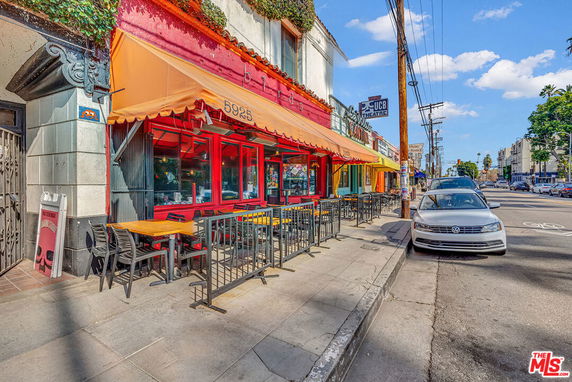 Street view of a building with a colorful facade and outdoor seating area.