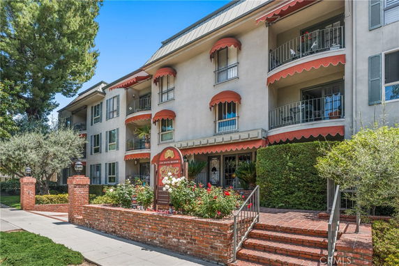 Front view of a multi-story residential building with balconies and a brick entrance.