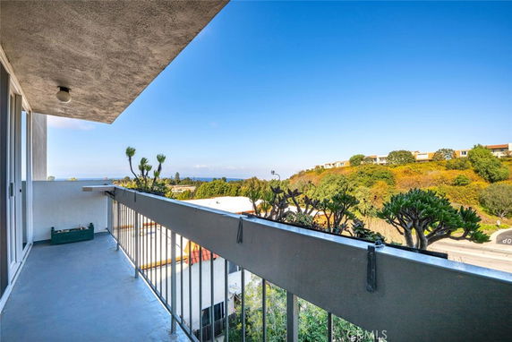 Balcony view overlooking surrounding greenery and distant buildings.