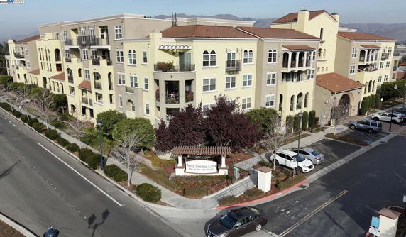 Front view of a multi-story apartment building with balconies and a curved entrance.