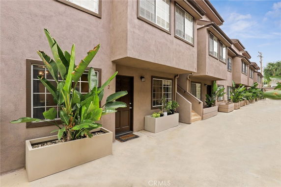 Front view of a townhouse row with multiple units and potted plants.