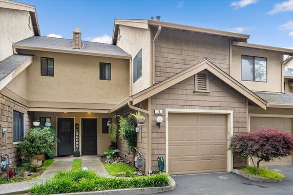 Front view of a multi-story townhouse with a garage and entrance pathway.