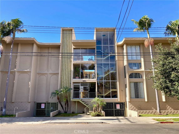 Front view of a multi-story building with large windows and palm trees.
