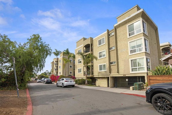 Front view of a multi-story apartment building with large windows and a garage entrance.