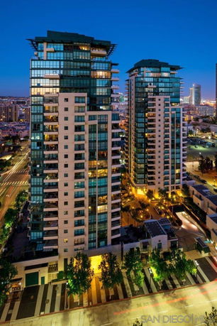 Front view of two tall residential towers with illuminated windows at night.