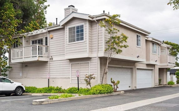 Front view of a two-story residential building with a balcony and double garage.
