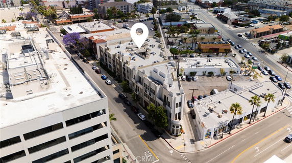 Aerial view of a city featuring multiple buildings, roads, and parked cars.
