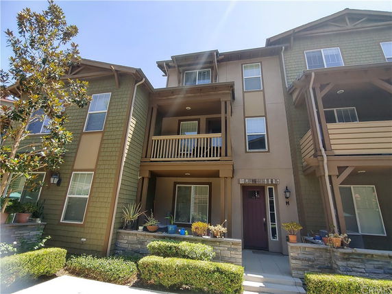 Front view of a multi-story house with a balcony and stone accents.