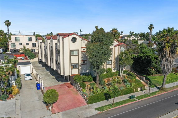 Front view of a multi-story apartment building with a driveway and landscaped garden.