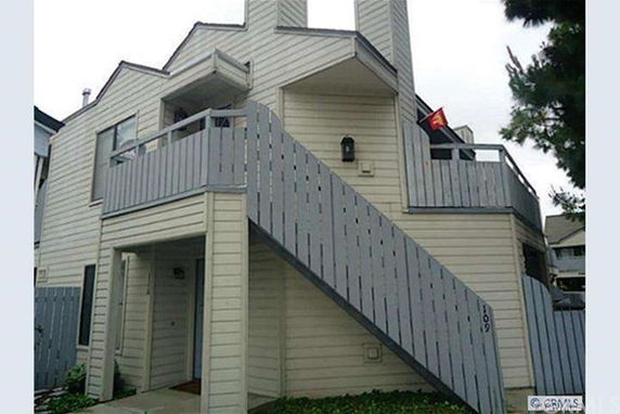 Front view of a multi-story house with exterior staircase and chimney.