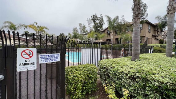 Outdoor view of a swimming pool with surrounding greenery and a no smoking sign.