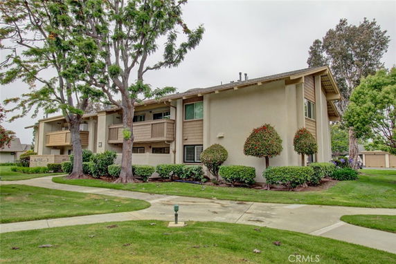 Front view of a two-story residential building with balconies and trees.