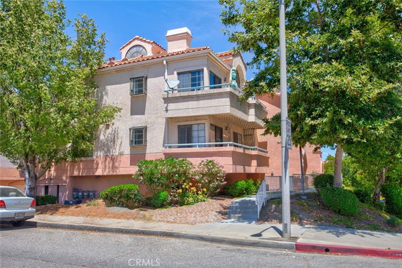 Front view of a multi-story building with balconies and a tiled roof.