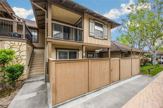 Front view of a two-story house with a balcony and fenced patio.
