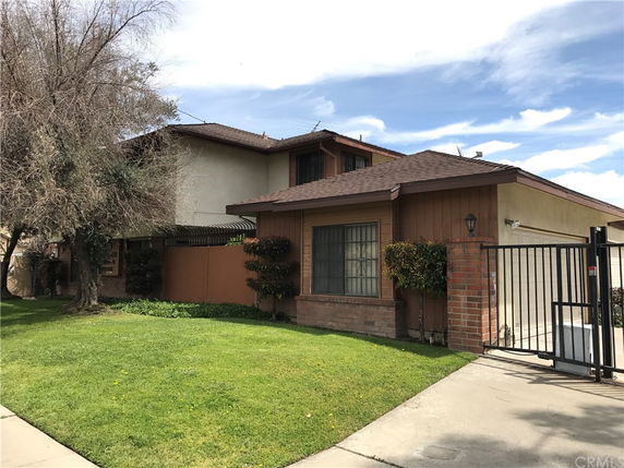 Front view of a two-story house with large windows and a gated driveway.