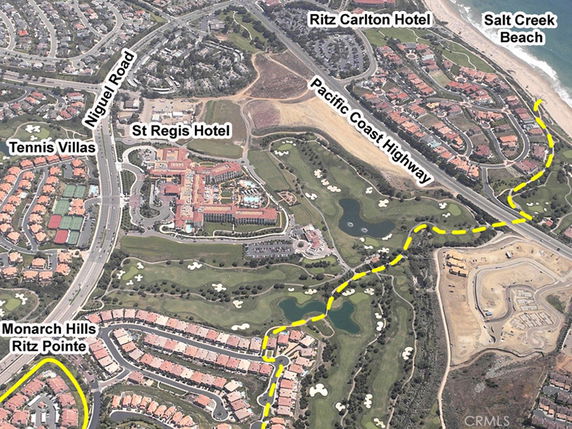 Aerial view of coastal area with hotels, a highway, golf course, and residential areas.