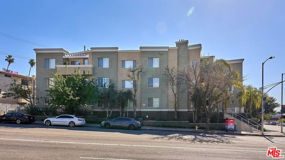 Front view of a multi-story apartment building with a flat roof and multiple windows.