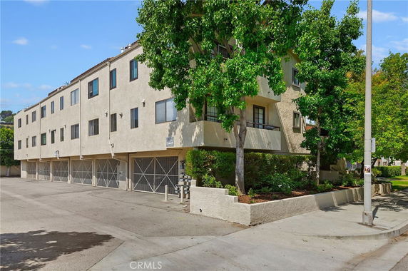 Front view of a multi-story apartment building with a row of garages on the ground floor.