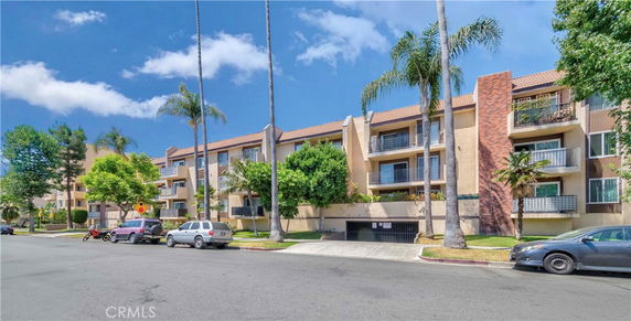 Front view of a multi-story apartment building with balconies and a brick facade.