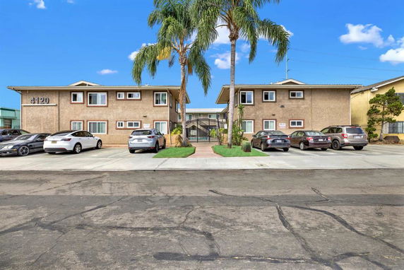 Front view of a two-story apartment building with parking area in front.