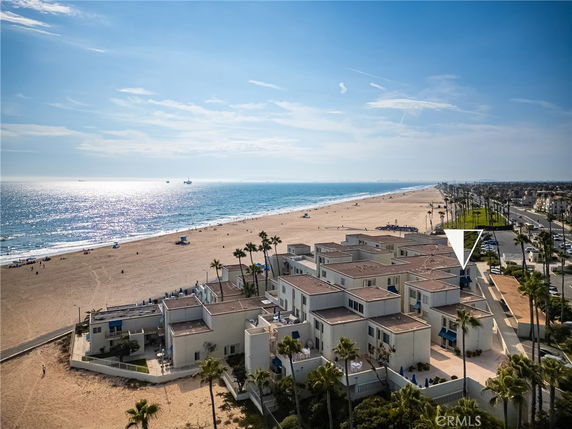 Panoramic view of a beachfront area with modern buildings and an expansive sandy beach.