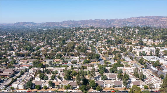 Wide angle view of a residential area with houses and greenery, hills in the background.