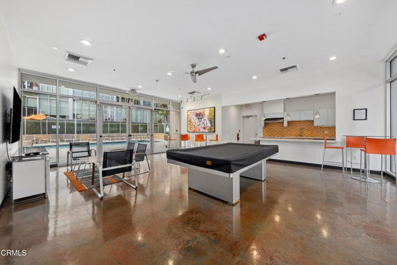 Recreation area with a pool table, seating, and kitchenette.