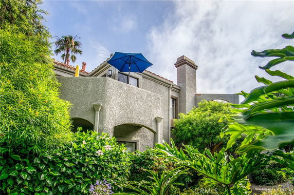 Front view of a multi-story house with a balcony and a patio umbrella.