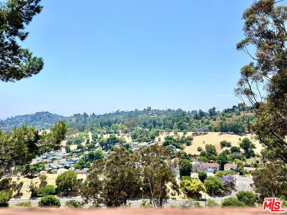 Wide-angle view of a scenic landscape with hills and scattered houses in the background.